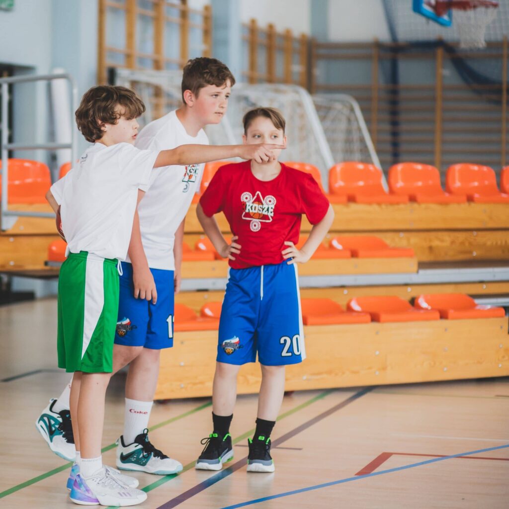 Trzech chłopaków stoi przed boiskiem