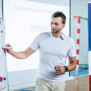 Trener Tomek rozpisuje taktykę na tablicy.